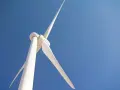 Białe turbiny wiatrowe obracają się na tle błękitnego nieba, czerpiąc energię z wiatru.