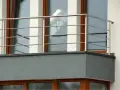 Nowoczesne mocowanie balustrady od czoła balkonu, wykonane ze stali nierdzewnej, z widocznymi czterema poziomymi prętami.