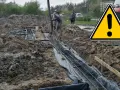 Pracownicy wylewają beton do wykopu, tworząc stopę fundamentową. Widać zbrojenie i folię.