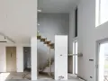 Nowe schody dywanowe w nowoczesnym domu w trakcie budowy. Drewniane stopnie kontrastują z betonową ścianą.