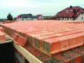 Budowa stropu ackermana z pustaków ceramicznych. W tle domy jednorodzinne.