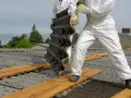 Osoby w kombinezonach ochronnych usuwają eternit. To pokazuje, co to jest azbest i jak wygląda.