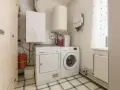 Funkcjonalne pomieszczenie gospodarcze z pralką, suszarką, bojlerem i szafą.