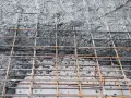 Zbrojenie fundamentów z betonu. Siatka z prętów stalowych pokryta świeżą masą betonową, gotowa do utwardzenia.