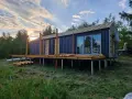 Nowy bungalow na palach, z drewnianym tarasem i dużymi oknami, w trakcie budowy.
