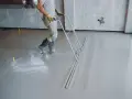 Budowlaniec wyrównuje świeży **miksokret** za pomocą specjalnego narzędzia.