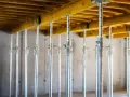 Metalowe podpory budowlane podtrzymują żółtą konstrukcję stropu. Wieniec budowlany w akcji.