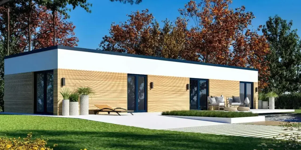 Nowoczesny dom modułowy 100m2 cena pod klucz, z drewnianą elewacją i dużymi przeszkleniami, otoczony zielenią i jesiennymi drzewami.