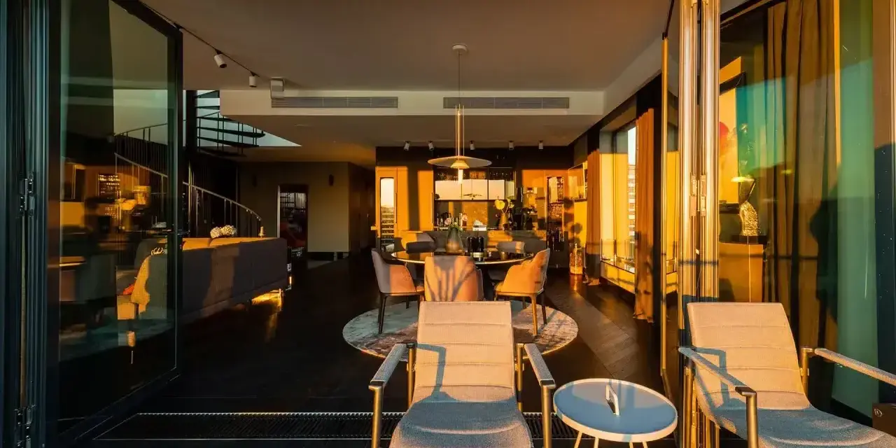Luksusowe penthousy oferują przestronne wnętrza z widokiem na zachód słońca. Widać tu salon, jadalnię i taras z meblami.