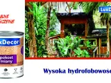 Puszka pokostu Iniany LuxDecor na tle tropikalnego domku. Produkt podkreśla naturalny kolor drewna i chroni przed wodą.