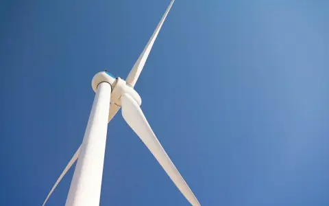 Białe turbiny wiatrowe obracają się na tle błękitnego nieba, czerpiąc energię z wiatru.