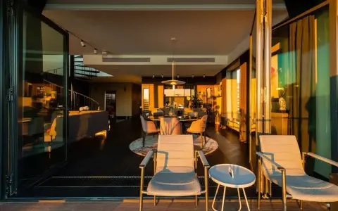Luksusowe penthousy oferują przestronne wnętrza z widokiem na zachód słońca. Widać tu salon, jadalnię i taras z meblami.