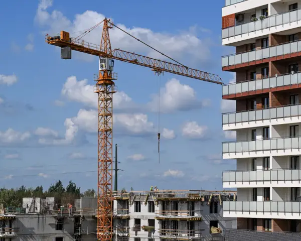 Budowa nowego osiedla przez lex deweloper. Żuraw budowlany pracuje przy nowoczesnym bloku mieszkalnym.