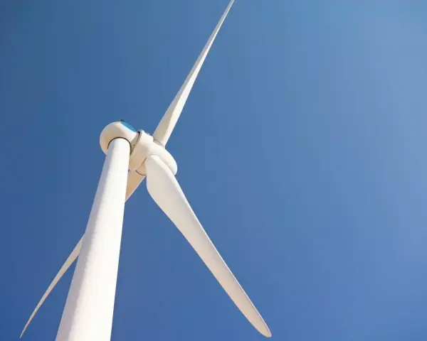 Białe turbiny wiatrowe obracają się na tle błękitnego nieba, czerpiąc energię z wiatru.