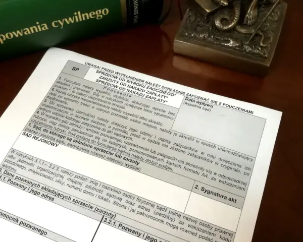 Zielona księga z tytułem "Kodeks postępowania cywilnego" i dokument z polami do wypełnienia.
