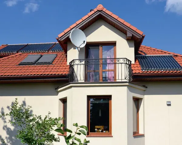 Elegancki wykusz w domu z balkonem i oknami, na dachu panele słoneczne.