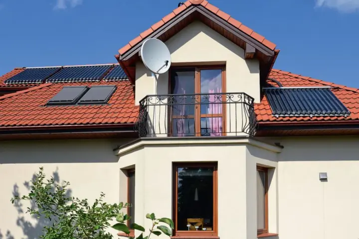 Elegancki wykusz w domu z balkonem i oknami, na dachu panele słoneczne.