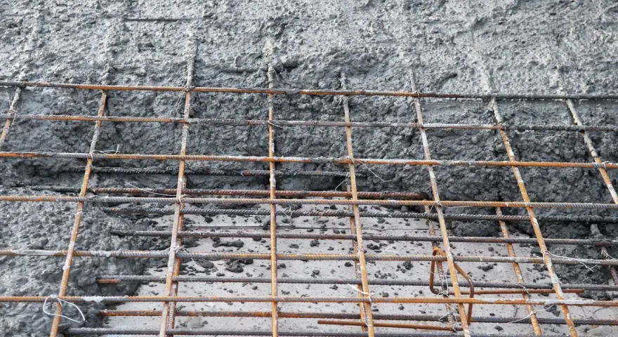 Zbrojenie fundamentów z betonu. Siatka z prętów stalowych pokryta świeżą masą betonową, gotowa do utwardzenia.