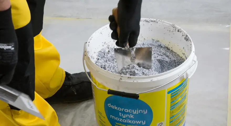 Mieszanie dekoracyjnego tynku mozaikowego w wiadrze. To pierwszy krok, jak zrobić tynk mozaikowy, by uzyskać efektowną elewację.