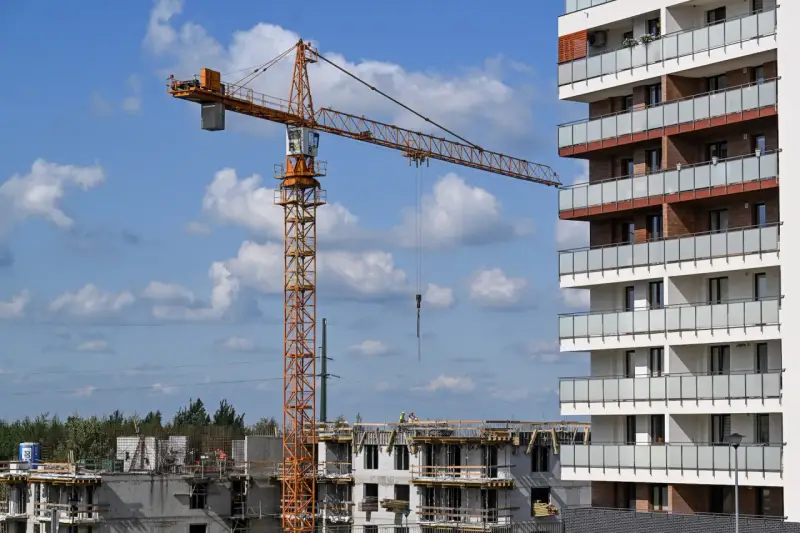 Budowa nowego osiedla przez lex deweloper. Żuraw budowlany pracuje przy nowoczesnym bloku mieszkalnym.