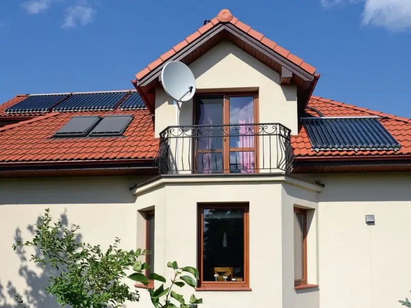 Elegancki wykusz w domu z balkonem i oknami, na dachu panele słoneczne.